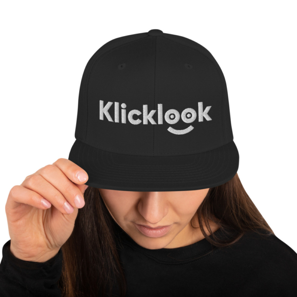 A young woman is swearing stylish Klicklook Black Snapback.